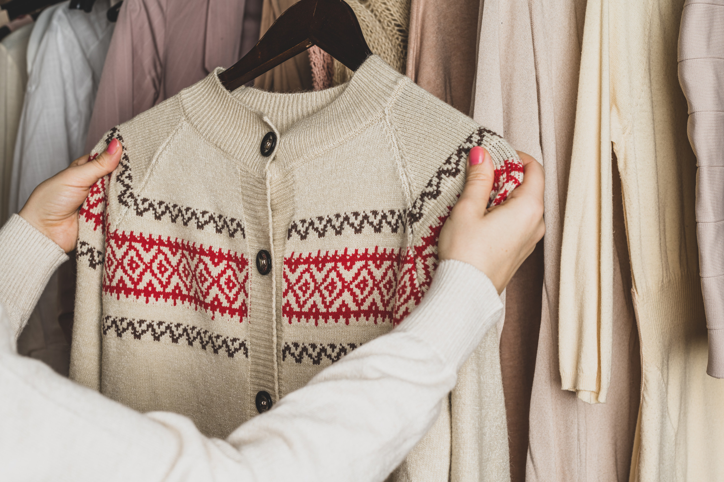 Woman choosing woolen sweater with christmas ornament in home cupboard. Season concept winter-fall-closet